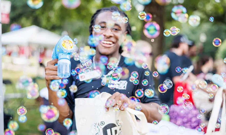 UP staff holding a UP bag and smiling, surrounded by bubbles